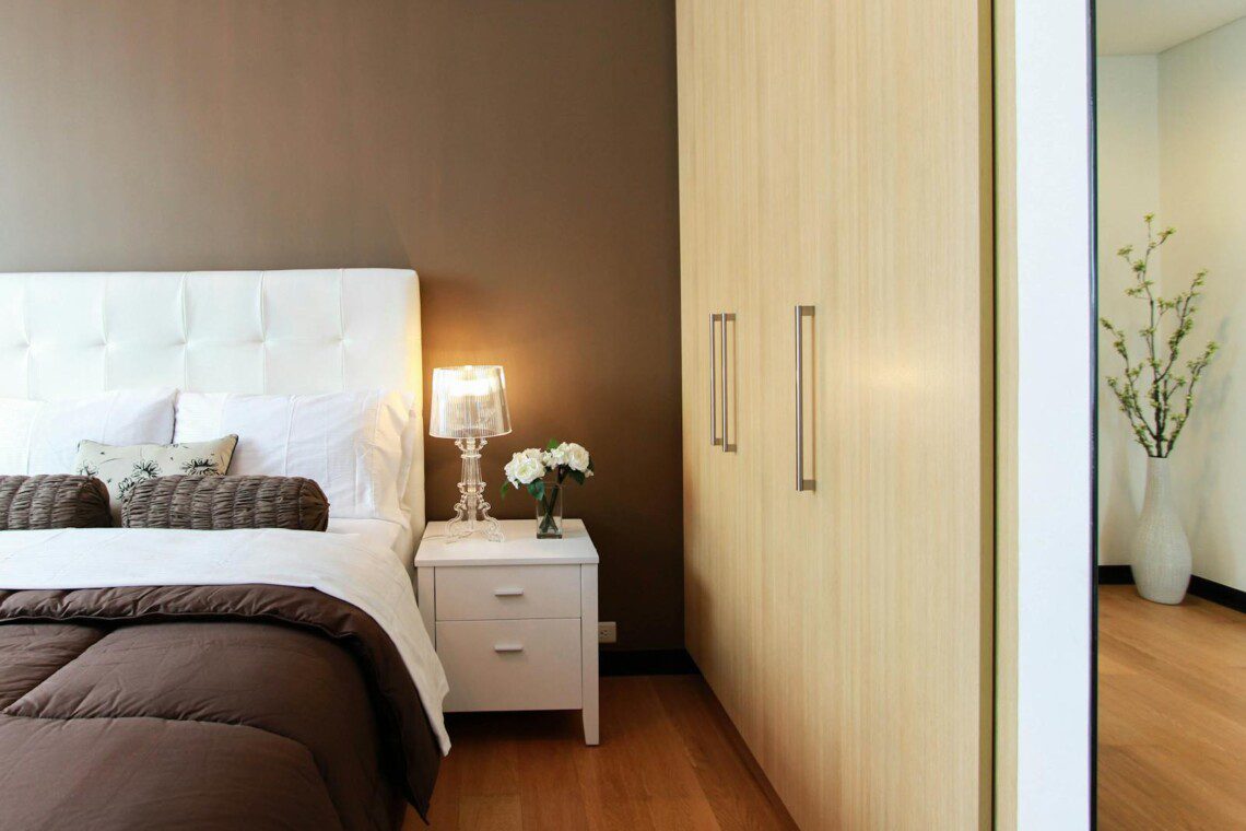 White Bed Next to White Accent Table